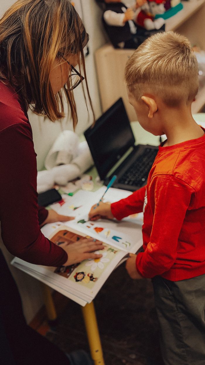 about-img Teacher assisting a child with educational activities in a learning environment.