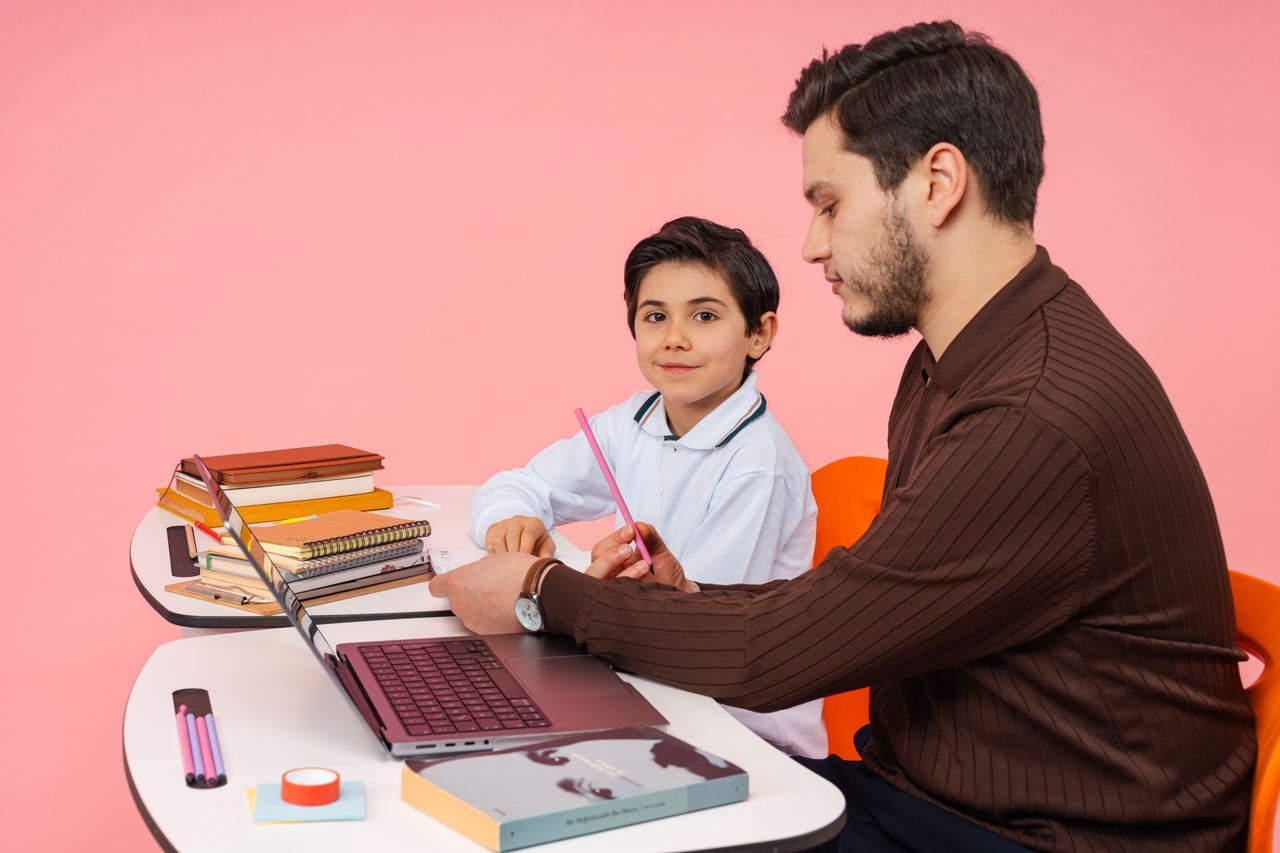 ours-journey A teacher assists a student in a colorful classroom setting, fostering learning and education.