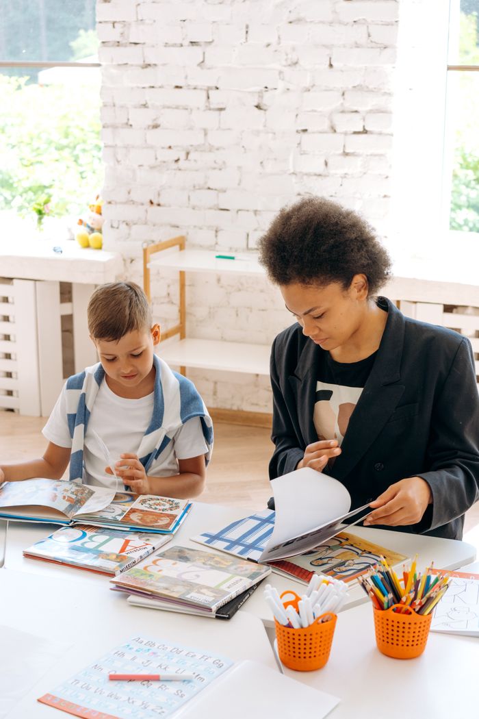 our-experience A teacher and student collaborate on reading activities in a sunlit classroom.