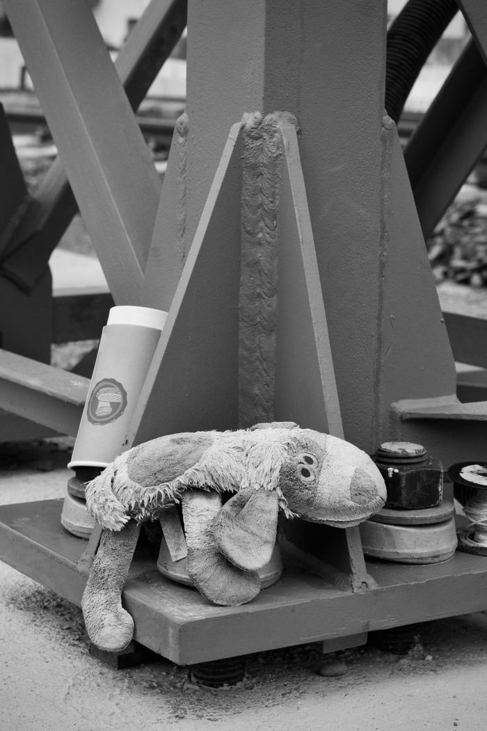 A discarded stuffed toy under a metal structure, conveying nostalgia.